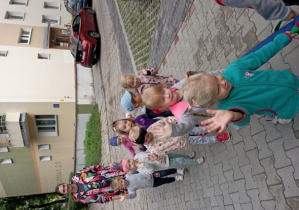 Dzieci machają do zdjęcia idąc po chodniku